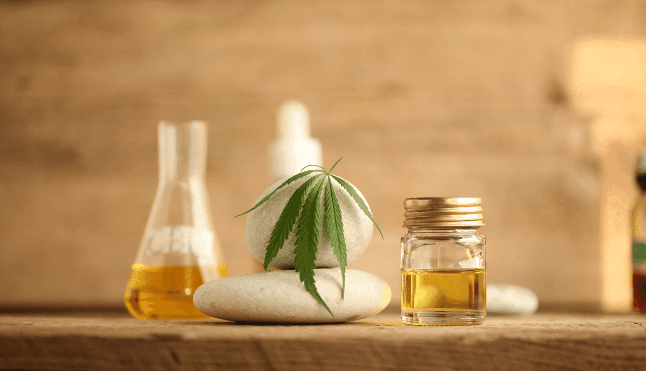 Flasche mit Hanföl und Hanfblatt auf einem Holzuntergrund.